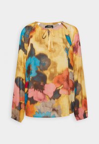 Blouse à manches longues multicolore avec des motifs floraux jaunes, bleus, roses et gris. Tissu doux avec un col rond et un détail noué.