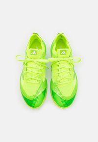 Neonowe zielone buty sportowe z teksturowanym wzorem, z cienkimi sznurowadłami i metką z logo. Podeszwa ma lekki zakręt dla lepszej wydajności.