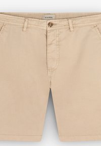 Beige puuvillashortsit, joissa on edessä vetoketju ja nappikiinnitys, vyölenkit ja kaksi sivutaskua. Sileä pinta ja siisti muotoilu.