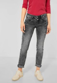 Grå denimjeans med en bleknad tvätt, slim fit, uppvikt bräm och knappstängning. Matchat med krämfärgade sneakers med texturerat tyg.