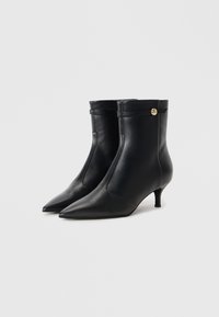 Bottines en cuir noir avec des bouts pointus, des talons kitten et un accent de bouton doré. Texture lisse et design élégant avec une tige ajustée.