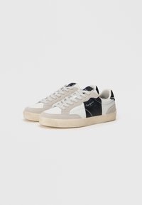 Scarpe sportive in suede e pelle grigio, bianco e nero. Presentano una chiusura con lacci, una parte anteriore traforata e una suola in gomma. Dettagli del logo discreti.