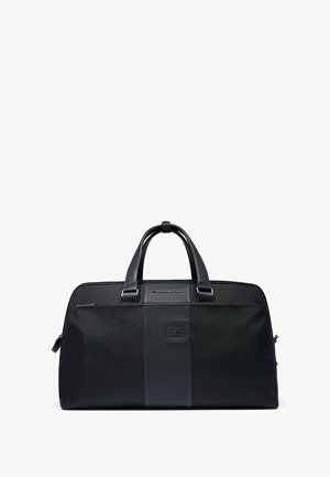 Black duffel bag featuring a textured fabric with smooth leather accents, dual handles, front zippered pocket, and logo detail.