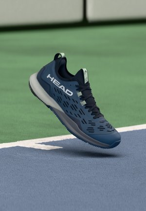 Scarpa da ginnastica blu con tomaia in mesh, caratterizzata da dettagli neri e motivi traforati. Marchio bianco sul lato, con suola ammortizzata.