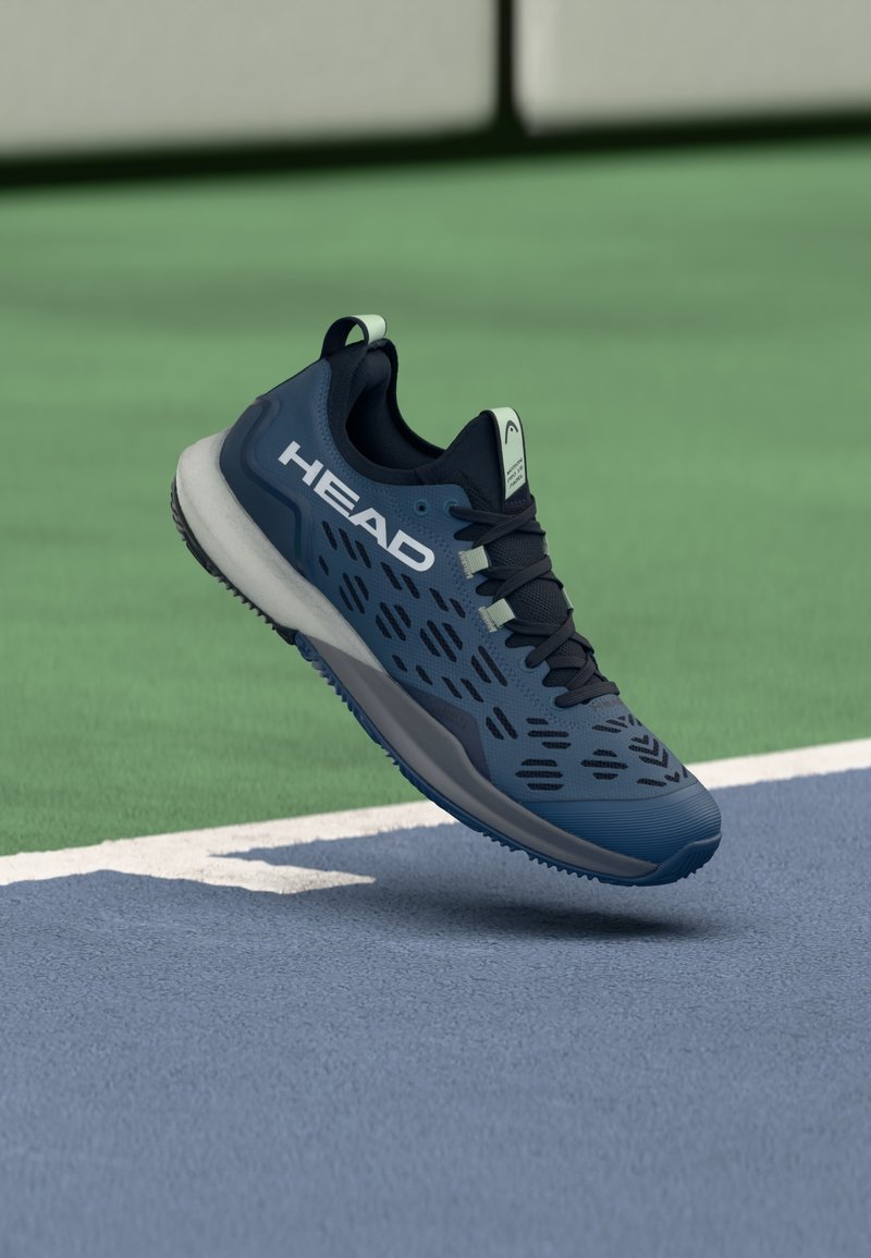 Niebieski but sportowy z siateczkową cholewką, wyposażony w czarne akcenty i wycięte wzory. Białe logo po boku, z amortyzowaną podeszwą.