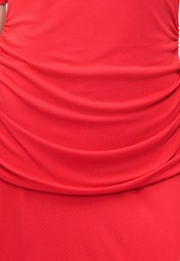 Κόκκινο φόρεμα με δι gathered υφασμάτινες λεπτομέρειες, απαλή υφή και εφαρμοστή σιλουέτα, κατάλληλο για ένα ευρύ φάσμα περιστάσεων. Πλένεται στο πλυντήριο.