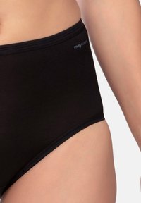 Culotte noire taille haute en tissu lisse. Présente une taille élastique douce avec des coutures minimales et une étiquette de marque sur le côté.