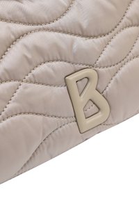 Quiltet beige skuldertaske i nylon med et fremtrædende beige bogstav "B" som hardware-detalje og subtile syningsmønstre.