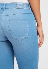 Lichtblauwe spijkerbroek met een patch pocket en gestikte details. De tailleband heeft een textuurlabel met de merknaam "TONI."