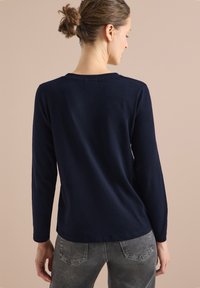 Námořnické tričko s dlouhým rukávem vyrobené z měkké tkaniny, s kulatým výstřihem a volným střihem. Jednoduchý design bez viditelných vzorů.
