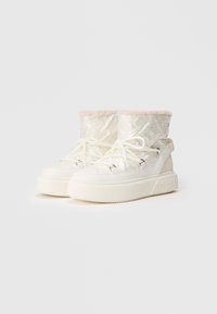 Botas de tobillo blancas con un superior texturizado, que cuentan con un forro de piel sintética rosa y una suela gruesa con acentos de patrón floral. Diseño con cordones.