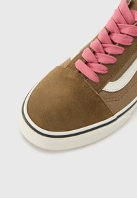 Barna velúr sneaker rózsaszín fűzőkkel, fehér oldalsávval és kerek orral. Kiemelkedő fekete talprészt díszít.