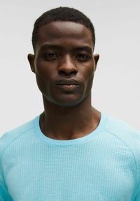 Vaaleansininen tekstuurinen pitkähihainen paita, jossa on pyöreä pääntie, hieno pistekuvio ja raglan-hihat. Sileä kangaspinta.