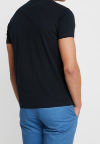 Svart bomull t-shirt med korta ärmar, rundad halsdesign, bärs med mönstrade blåa shorts med elastisk midja och fickor.