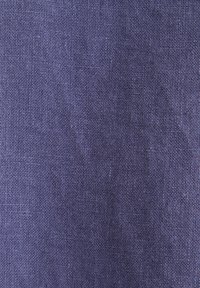 Tissu tissé bleu foncé avec texture visible et fibres étroitement tricotées, montrant de légères rides et des irrégularités naturelles du tissu.