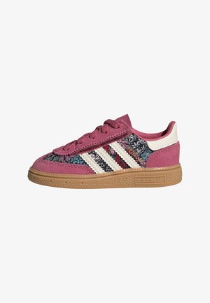 Lavtopet Adidas sneaker med pink ruskind, blomstret mønstret stof, hvide striber og gummisål.