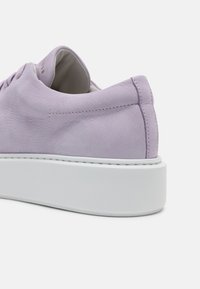 Lavendel lädersneakers med vadderad krage, vit plattformssula och subtila sömdetaljer. Mjuk textur och rundad form.