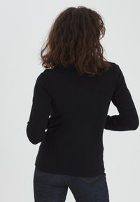 Maglietta nera a maniche lunghe con un design aderente e scollatura rotonda, realizzata in un materiale morbido. Texture liscia, con un colore uniforme e senza pattern visibili.