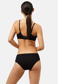 Conjunto de sujetador negro y braguita a juego, confeccionados con tela suave. El sujetador tiene tirantes ajustables y cierre de gancho; la braguita presenta un sutil borde de encaje.