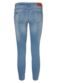 Jeans ajustados de color azul claro con una textura de denim suave. Presenta dos bolsillos traseros y un parche de cuero marrón en la cinturilla.