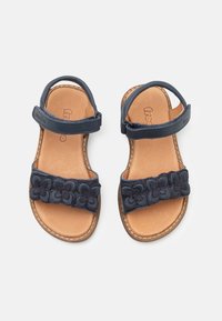 Sandales en cuir navy avec une sangle en tissu floral, bouclerie réglable à la cheville et semelle intérieure en cuir naturel. Semelle plate, design décontracté.