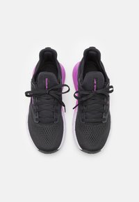 Un par de zapatillas de running Reebok negras y moradas con tela de malla y cordones, vistas desde arriba sobre un fondo blanco.