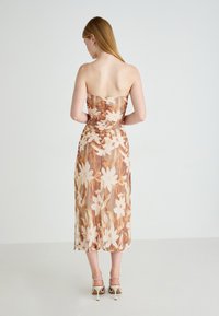 Strapless bloemenjurk in aardetinten, met een gerimpelde bodice en een vloeiende rok, gemaakt van gestructureerde stof en met een lengte tot halverwege het onderbeen.