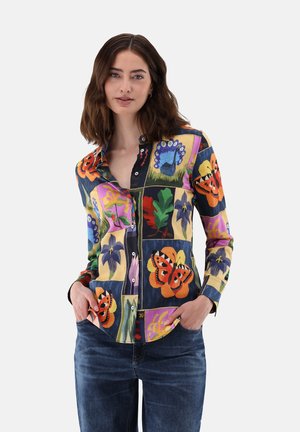 Collared button-up shirt featuring a multicolored floral and butterfly pattern, constructed from a textured fabric. Pockets at the waist.