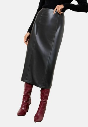 Black leather midi skirt with a sleek design, featuring visible stitching details. Paired with knee-high burgundy crocodile-embossed boots.
