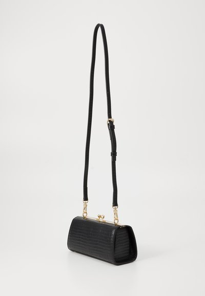 Črna torbica iz krokodilne teksture s strukturirano obliko, zlatih kovinskih delov in nastavljivim trakom. Zapenjanje vključuje klasično zaponko.