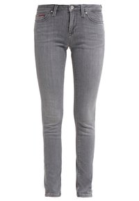 Jeans de mezclilla gris con corte slim, cierre de botón, bolsillos estándar y un sutil acento rojo en el bolsillo delantero.