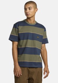 Short-sleeve T-shirt in green, navy, and beige horizontal stripes. Features a chest pocket with a logo patch and a crew neckline.