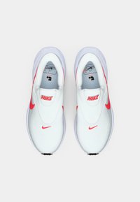 Nike slip-on αθλητικά παπούτσια με λευκό πλέγμα στο επάνω μέρος, κόκκινες λεπτομέρειες και επενδεδυμένο κολάρο. Στρογγυλή μύτη και ευέλικτη σόλα για άνεση.