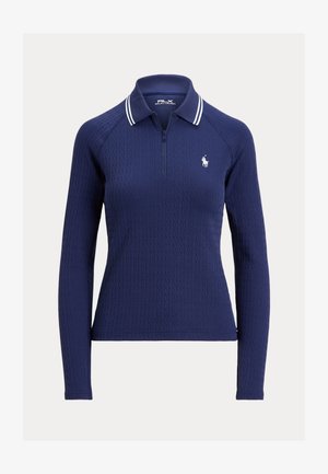 Camisa polo de manga larga azul marino con cuello con cremallera, textura de punto cableado y acentos de cuello con rayas blancas. Presenta un logo bordado en el lado izquierdo del pecho.