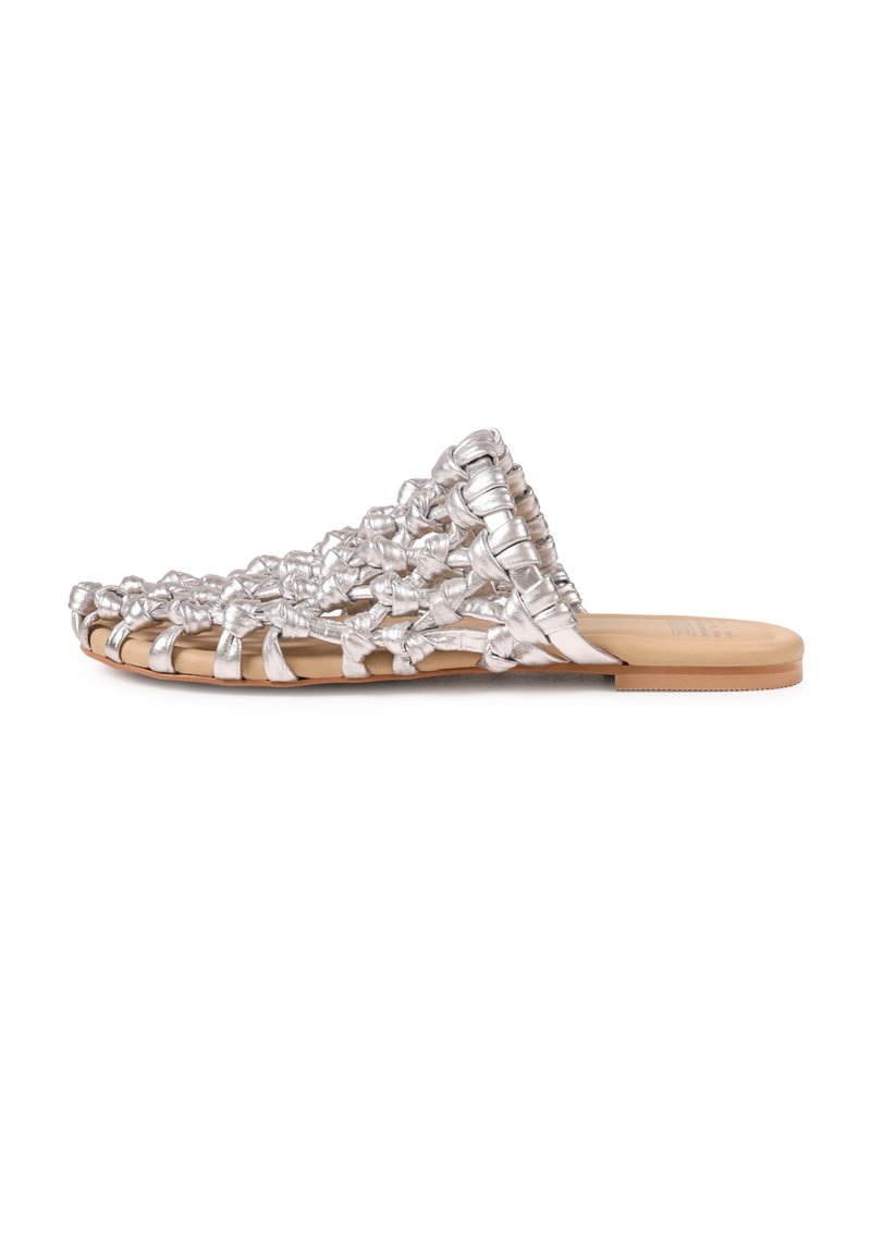 Sandale plate en cuir tressé argent avec des brides nouées et une semelle couleur fauve, vue de profil sur fond blanc.