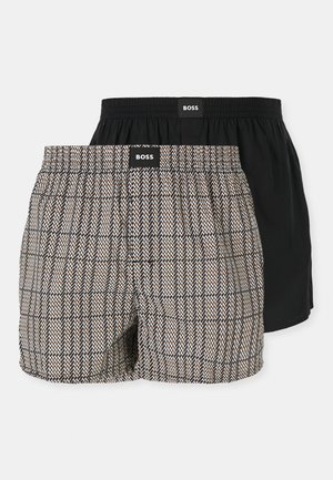 Schwarze und gemusterte beige Boxershorts mit elastischem Bund, auf dem das "BOSS"-Logo zu sehen ist. Das gemusterte Paar weist ein geometrisches Design auf.
