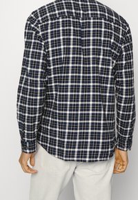 Navy and white plaid shirt, long sleeves, buttoned cuffs, back yoke detailing, slightly curved hem, made from breathable fabric.