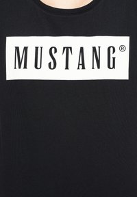 Černé tričko s bílým obdélníkovým grafikou obsahující slovo "MUSTANG" v tučných černých písmenech. Vyrobeno z měkké bavlněné tkaniny.