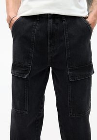 Schwarze Cargo-Jeans mit geradem Schnitt, zwei Seitentaschen und einer glatten Textur mit sichtbaren Nähdetails.