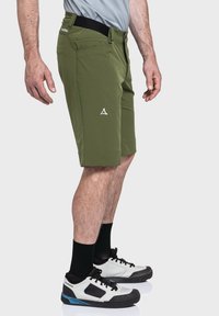 Grüne, knielange Shorts in Slim Fit aus leichtem Stoff. Sie haben einen schwarzen Bund und ein weißes Logo-Detail auf der Vorderseite.