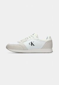 Witte en lichtgrijze sneaker van suede en synthetisch materiaal, met een zwart logo, ronde neus en gestructureerde zool.