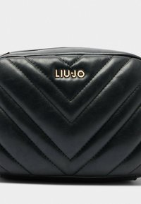 Schwarze, gesteppten Lederpouch mit Chevron-Muster und goldfarbenem LIU JO-Logo, das zentral auf der Vorderseite vor einem hellgrauen Hintergrund platziert ist.