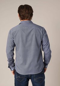 Langärmelig shirt in marineblauw met een geometrisch wit patroon. Heeft een klassieke kraag en knoopmanchetten, gemaakt van een soepele stof.