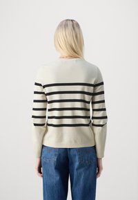 Helles beige Sweatshirt mit schwarzen horizontalen Streifen, Rundhalsausschnitt und langen Ärmeln. Kombinieren Sie es mit einer Jeans, die in der Taille sichtbar ist.