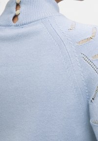 Jasnoniebieski sweter dzianinowy z wysokim dekoltem, z wycięciem z tyłu ozdobionym trzema dekoracyjnymi guzikami perłowymi oraz teksturowanym wzorem.