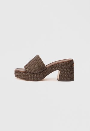 Brown woven platform mule with block heel and open toe, featuring a wide woven strap over the foot.