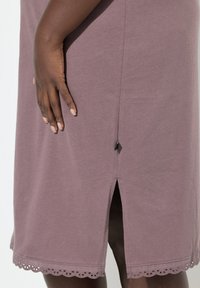 Abito di cotone viola con orlo scallop e fessura laterale. Presenta una superficie liscia e maniche corte, mostrando un design semplice e casual.