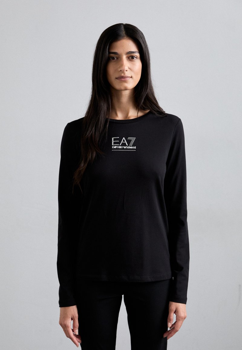 Zwarte lange mouwen shirt van zachte stof met een centraal wit logo ontwerp met de tekst "EA7" en "Emporio Armani". Eenvoudige, getailleerde vorm.