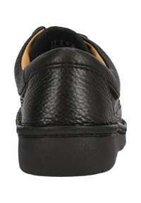 Chaussures en cuir noir avec une finition texturée, talon arrondi et intérieur clair en contraste. Détails cousus le long de la semelle.