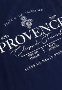 Tela azul marino con texto blanco "Provence", ilustración floral y frases "Plateau de Valensole", "Champs de Tournesol", años 1980 y 1990.